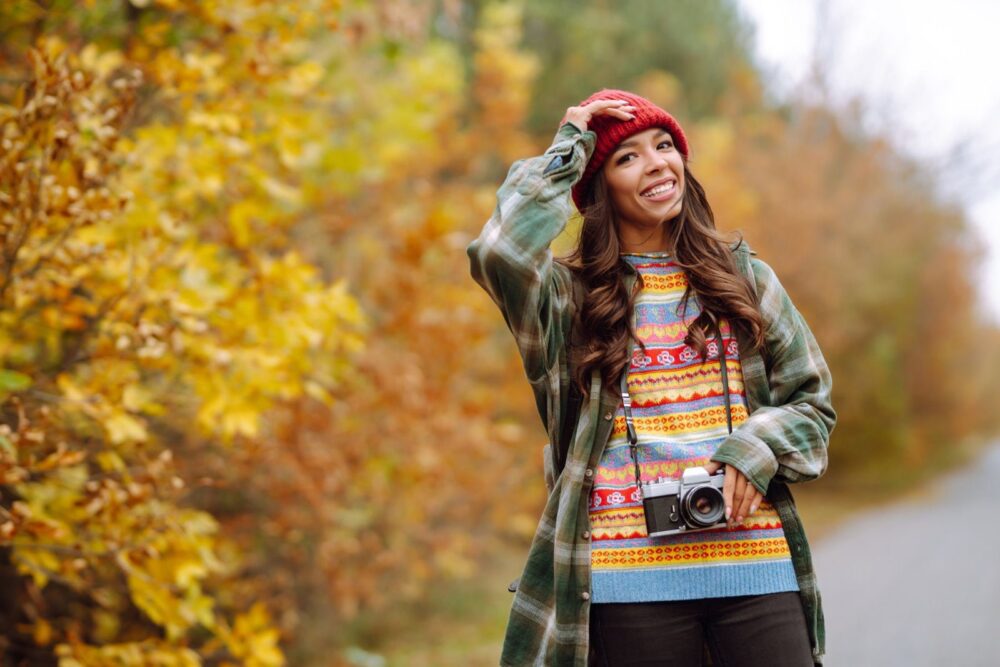 O tânără frumoasă este fotografiată cu o cameră retro. Odihnă, relaxare, călătorii, stil de viață.